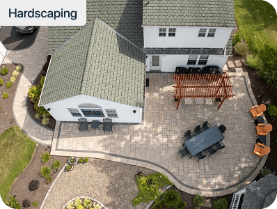 Aerial view of a curved paver patio with a pergola and outdoor dining set