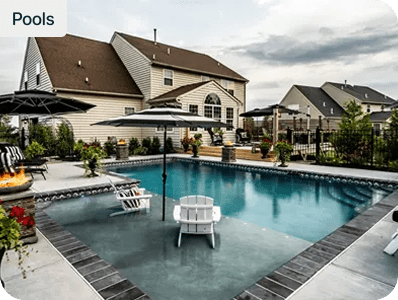 Custom inground pool and paver patio with a fire pit behind a two-story home