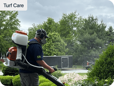 Blue Tree technician applying a backpack lawn and pest treatment to a residential property