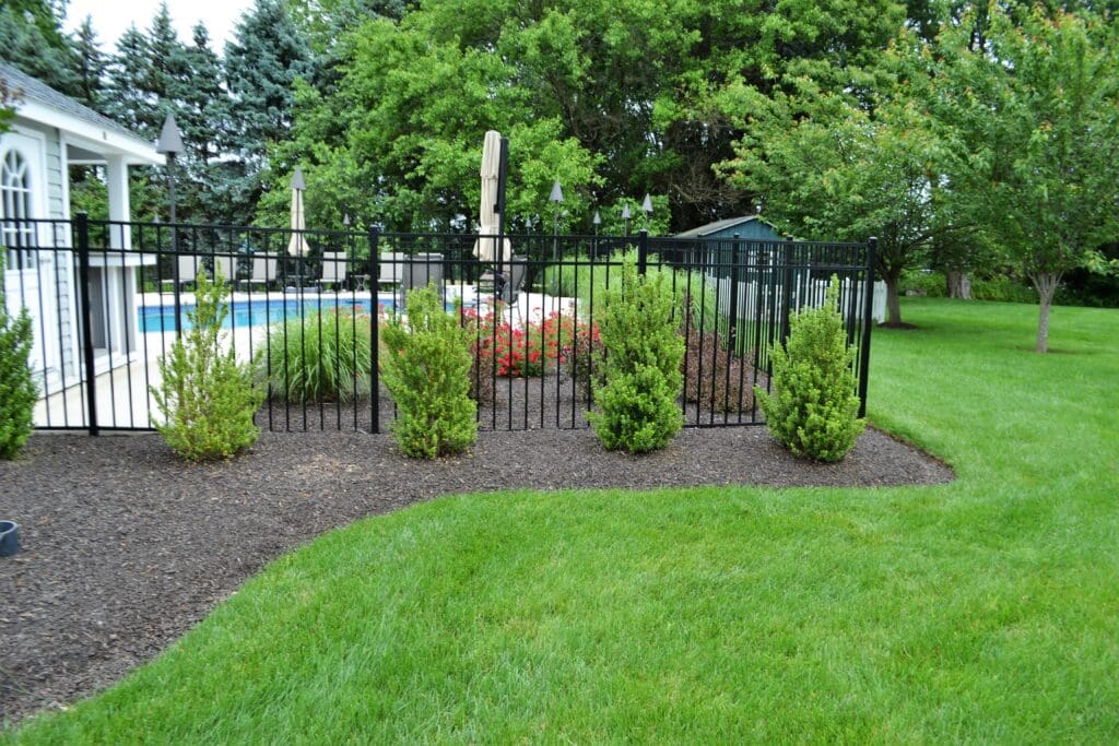 Green lawn beside curved planting beds and a black fence at a Blue Tree outdoor space.