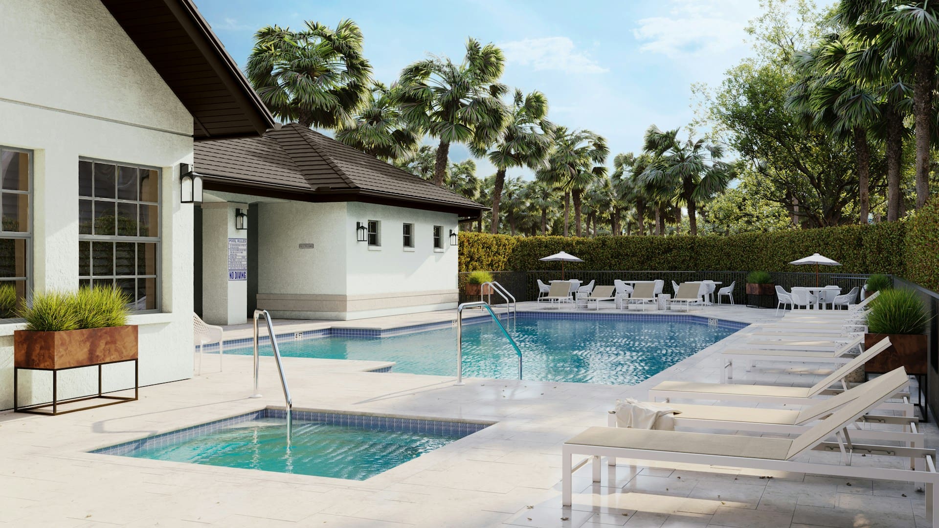 Outdoor swimming pool area with lounge chairs, a small hot tub, and tables with white umbrellas. Palm trees and greenery surround the pool, and a building with large windows is nearby under a sunny sky.