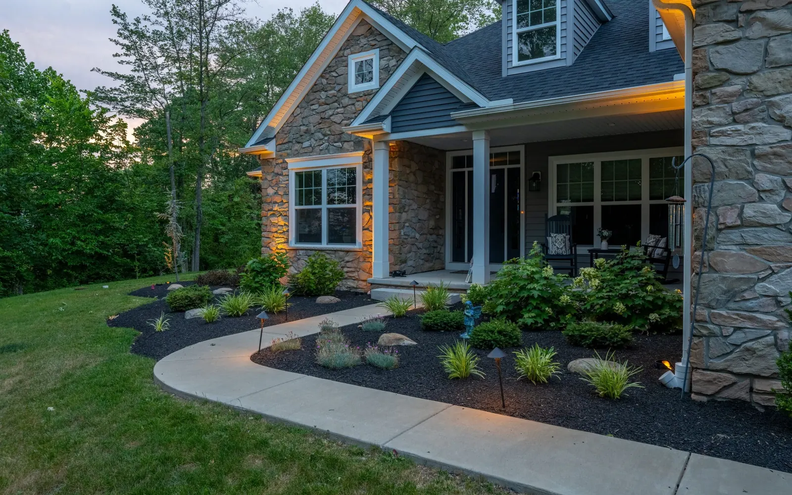 Finished front-yard landscape with a curved walk, layered plantings, and lighting in Pottstown, Pennsylvania by Blue Tree Outdoor Living