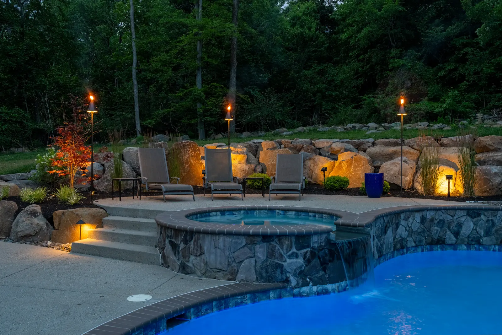 Raised spa, pool waterfall, and boulder wall at dusk in Pottstown, PA